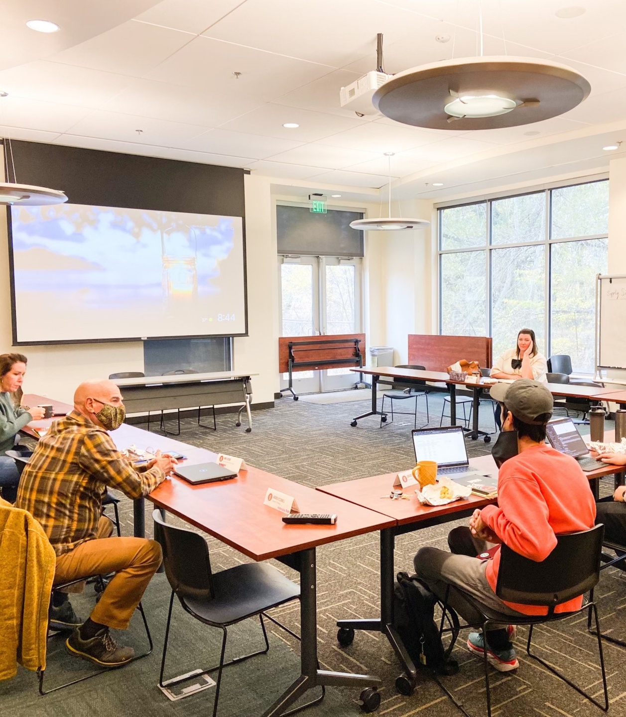 Business men and women sitting around a conference table with laptops