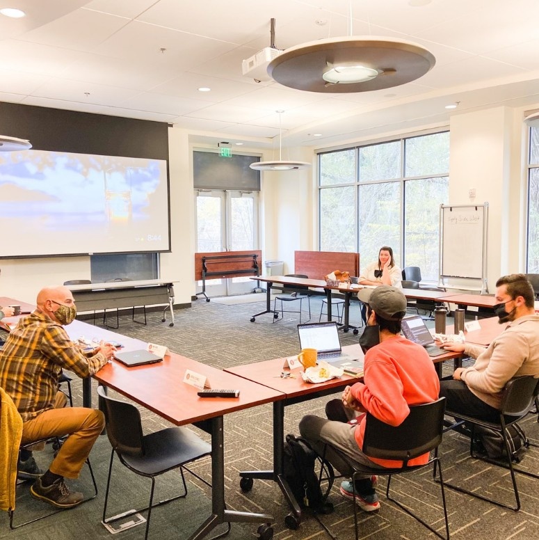 Business men and women sitting around a conference table with laptops