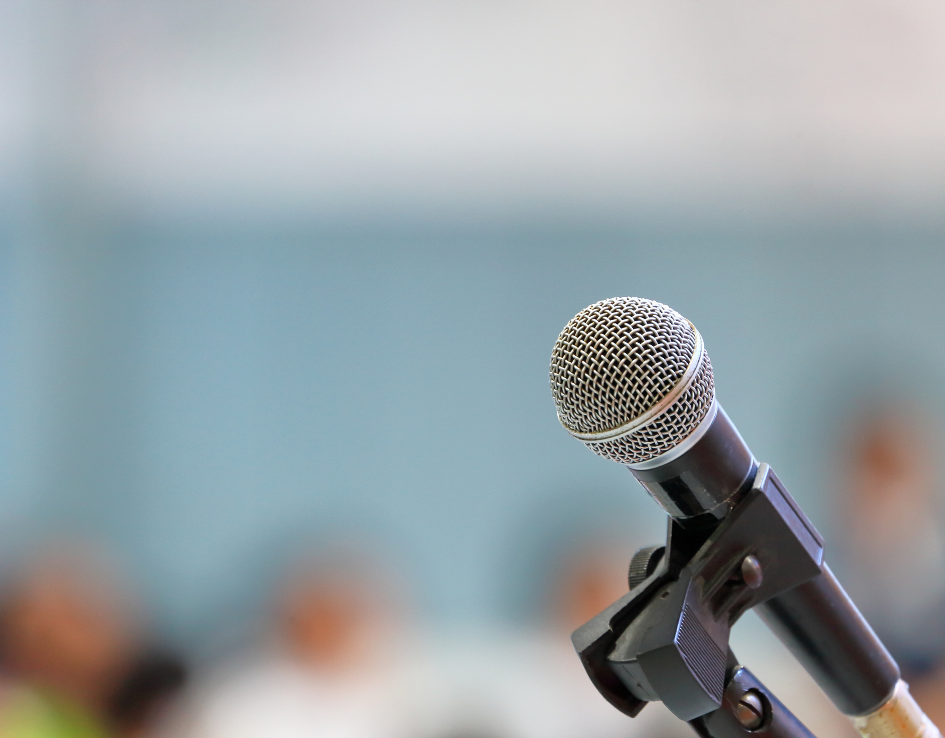 Photo of a microphone in front of an audience, which is blurred out